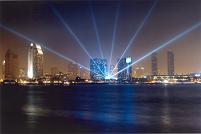 6 7kw beams fanned into the sky with a city scape in the background on the San Diego harbor